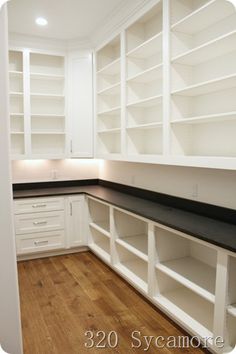 an empty kitchen with white cabinets and black counter tops, wood flooring and hard wood floors