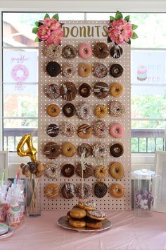 a table topped with lots of donuts on top of a pink cloth covered table