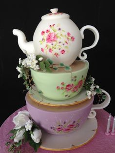 a three tiered cake decorated with flowers and a teapot