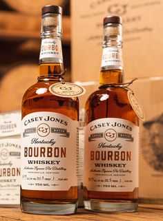 two bottles of bourbon sitting on top of a wooden table