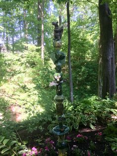 a water fountain in the middle of a forest filled with lots of plants and flowers