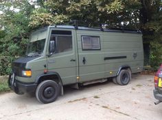 an army green truck parked in front of some trees