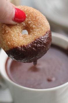 a person dipping chocolate into a doughnut