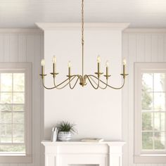 a chandelier hangs over a fireplace in a white room