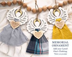 three wooden ornaments hanging from strings on a white cloth with text that reads memorial ornament add your loved ones clothing