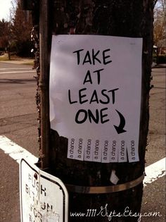 a sign on a telephone pole that has been vandalized with the words take at least one