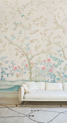 a white couch sitting in front of a wall with flowers painted on it's side