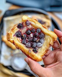 a person holding up a pastry with berries on it