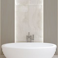 a white bath tub sitting next to a wall with black and white stripes on it