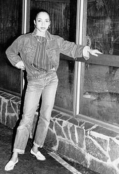 an old black and white photo of a woman standing in front of a door with her arms out