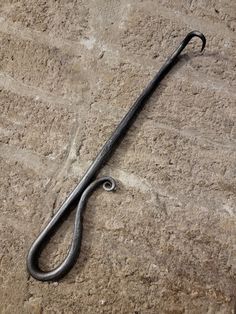 an old hook is laying on the ground with it's handle still attached to it