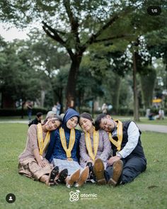 three people sitting on the ground in front of trees and grass with their arms around each other