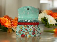 three small purses sitting on top of a table with flowers in the back ground