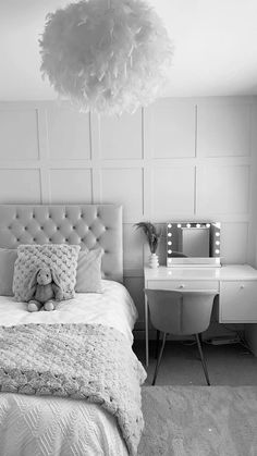 black and white photograph of a bedroom with a teddy bear on the bed in front of a vanity