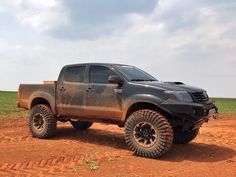 a large truck parked on top of a dirt covered field in the middle of nowhere