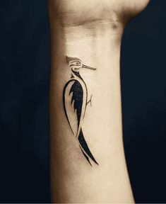 a black and white bird tattoo on the left inner arm, with an arrow in it's beak