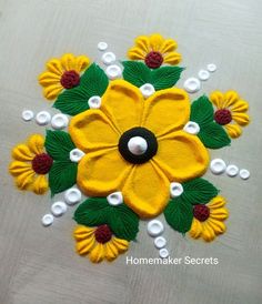 a yellow flower with green leaves and white pearls on the bottom is surrounded by beads