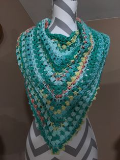 a mannequin wearing a multicolored crocheted shawl on display