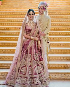 two people standing next to each other in front of stairs wearing wedding outfits and veils