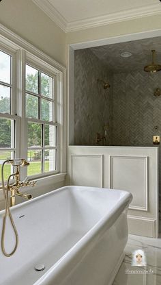 a large white bath tub sitting in a bathroom next to a window and shower head