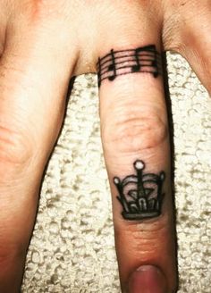 a person's finger with musical notes on it and a crown in the middle