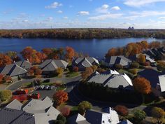 an aerial view of some houses by the water and trees with orange leaves on them