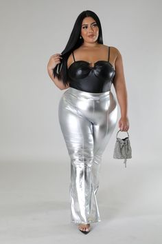 a woman in shiny silver pants and black top with her handbag on her hip