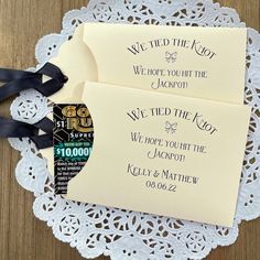 two wedding envelopes sitting on top of a doily