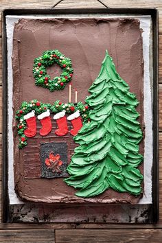 a chocolate cake decorated with christmas decorations and stockings on the fireplace is displayed in front of a wood paneled wall