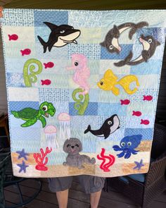 a person holding up a quilt with sea animals on it