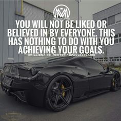 a black sports car parked in front of a building with an inspirational quote on it