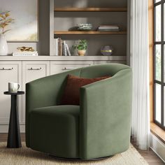 a green chair sitting on top of a rug in a living room next to a window