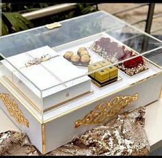 a white box with gold trimmings and some cookies in it on top of a table