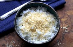 a bowl filled with white rice next to two spoons