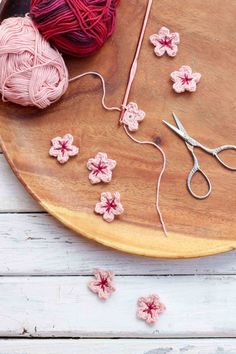 yarn and crochet on a wooden table with scissors, balls of yarn and flowers