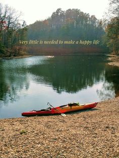 a red kayak sitting on the shore of a lake