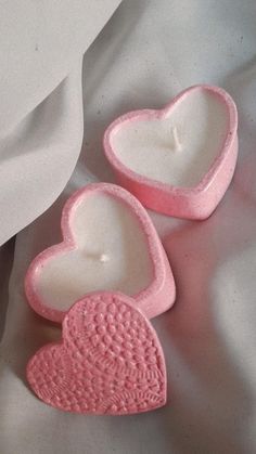 two heart shaped soaps sitting next to each other on a white cloth covered surface