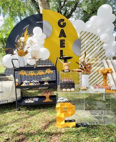 a table with balloons, cake and decorations on it in front of a yellow sign