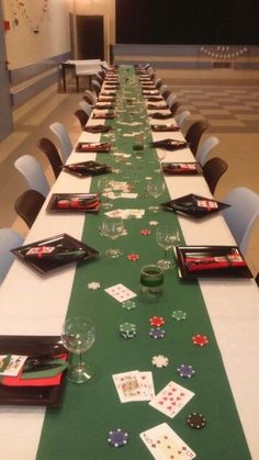 a long table is set up with playing cards and wine glasses on it for a casino themed party