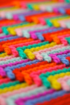 the colorful crocheted blanket is laying on the floor