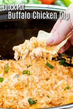 a hand dipping a tortilla chip into a pot of buffalo chicken dip with green peppers