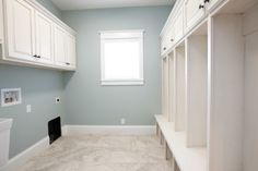 a bathroom with white cabinetry and drawers in it's center, next to a window