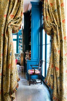 the room is decorated in blue and gold with drapes on the windowsills