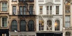 an image of a city street scene in the rain with buildings and fire escape ladders