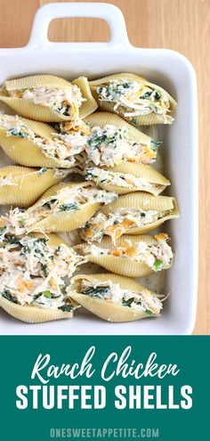 a white dish filled with stuffed shells covered in cheese and spinach on top of a wooden table