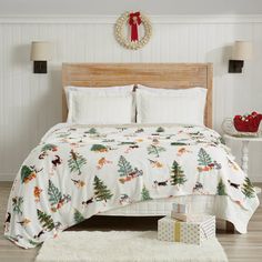 a bed with christmas decorations on it in a bedroom next to a table and two lamps