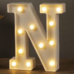 the letter n is lit up with lights on it's sides and sits on a table