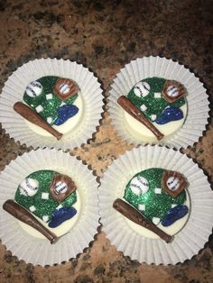 four cupcakes decorated like sports equipment on paper plates with green and white frosting