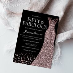 a black and pink glitter wedding card with a dress silhouette on it, sitting next to a white cloth