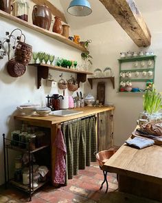 an old fashioned kitchen with lots of pots and pans on the shelf above the sink